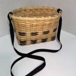 A woven reed basket with black accents and a black woven fabric scrap