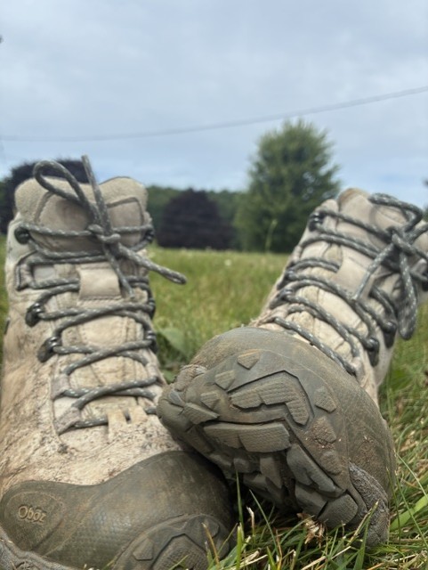 A pair of grey and muddy hiking boots